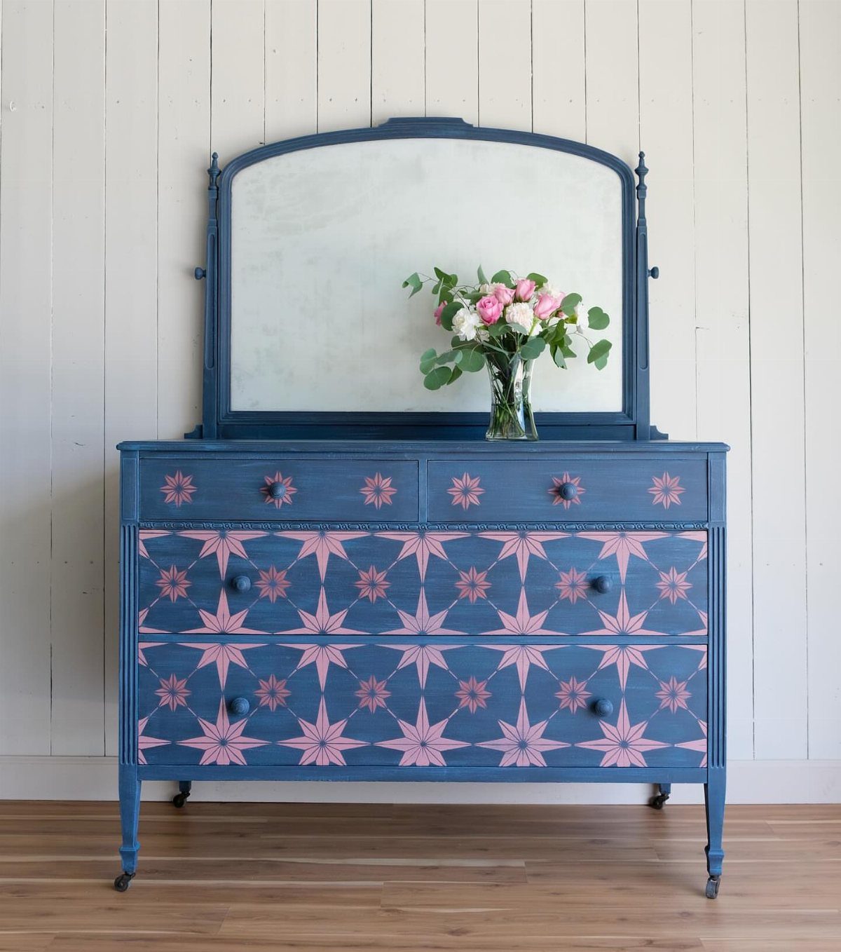 Blue painted dresser with pink star patterns and a matching mirror.