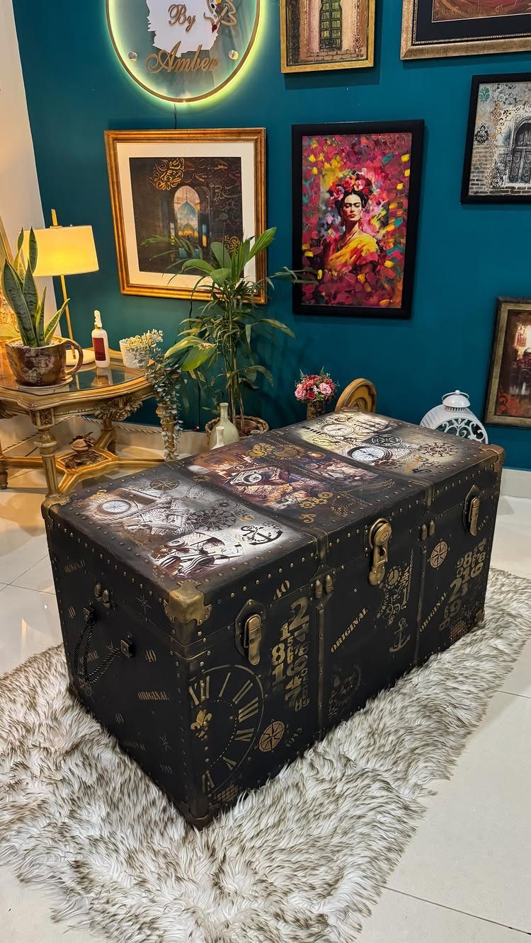 Black vintage steamer trunk with decorative decoupage art on the lid and gold latches.