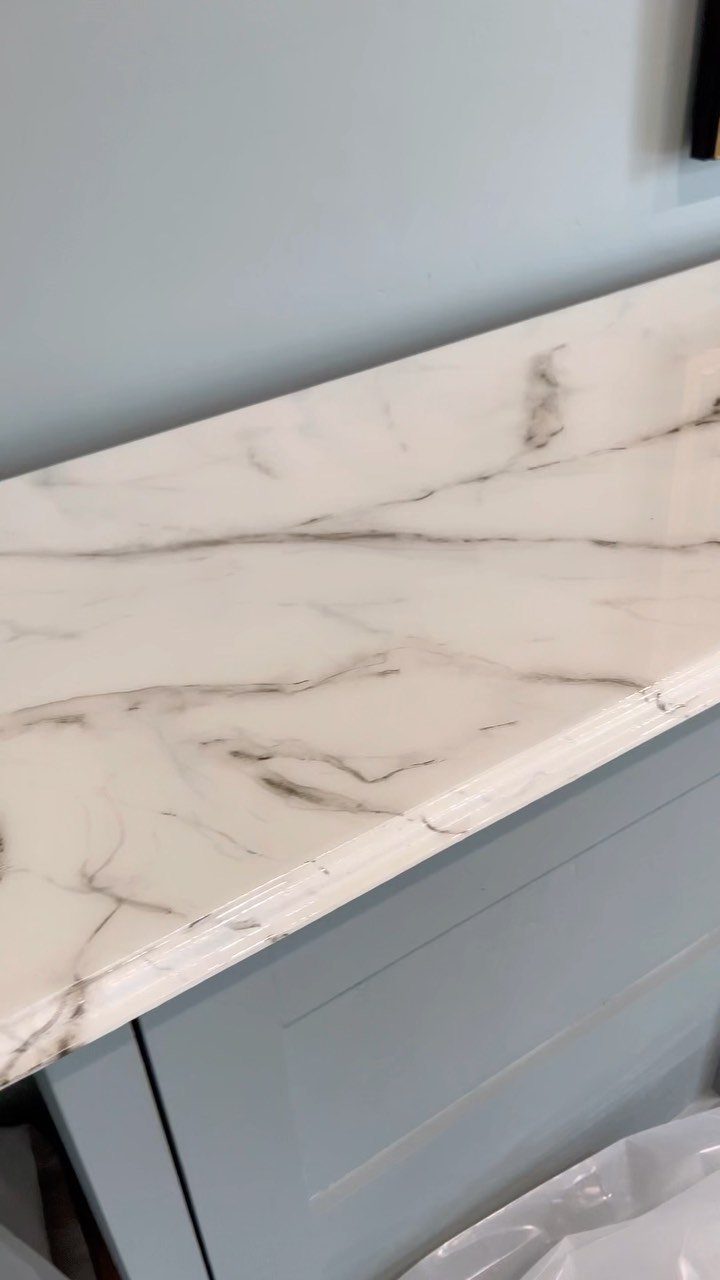 White furniture surface with grey faux marble veining on a grey cabinet.