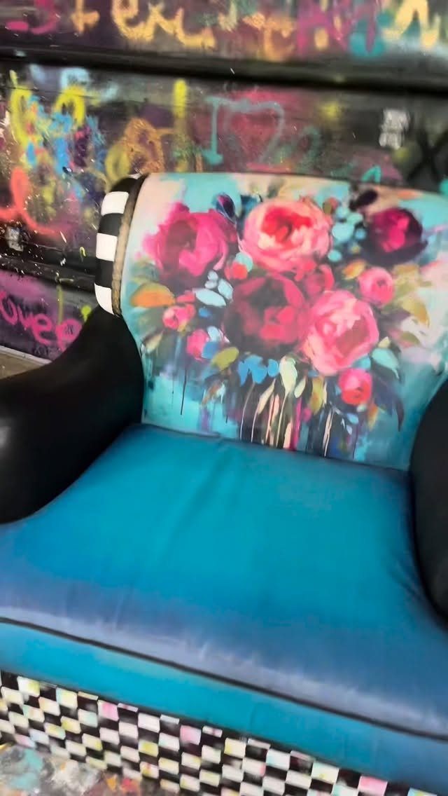Blue armchair with pink floral paintings on the backrest against a graffiti wall