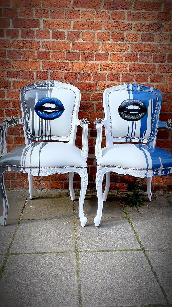 Two white upholstered armchairs featuring painted lips and blue paint drip designs.