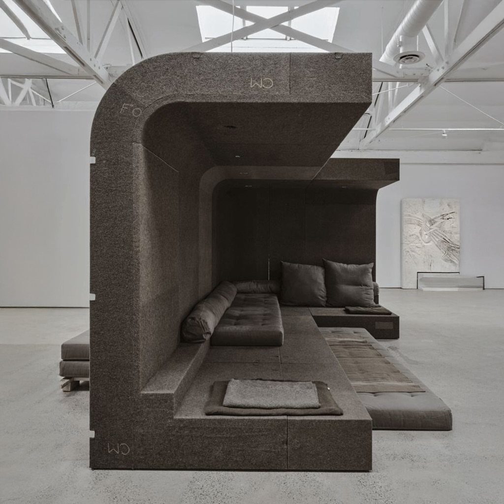Dark grey felted modular sofa with a curved canopy in a white gallery