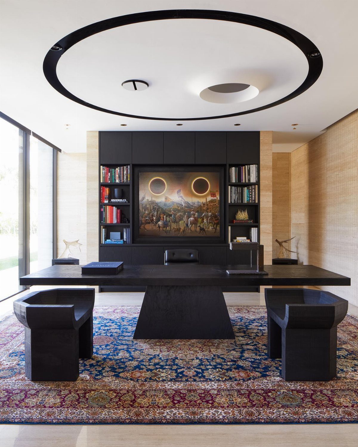 Heavy black minimalist desk and chairs on a colorful rug in a modern office
