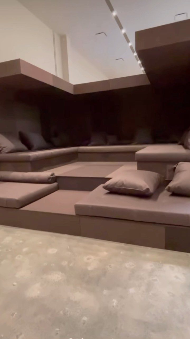 Modular brown leather seating platforms in a minimalist brutalist interior with concrete floors.