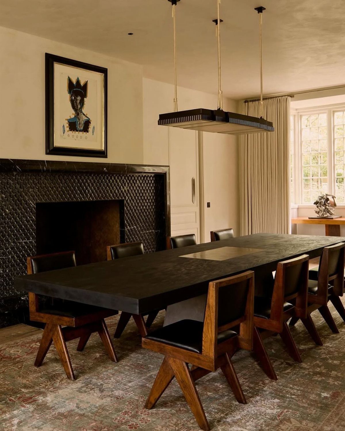 Monolithic dark dining table and angular wooden chairs in a minimalist interior