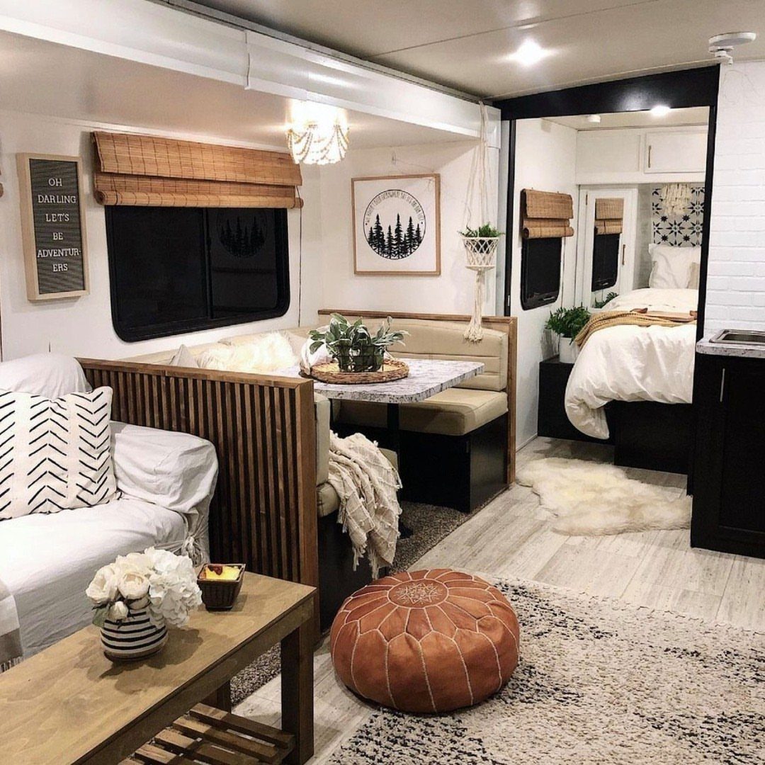 Decorated RV interior with white sofa, leather pouf, and patterned area rug.