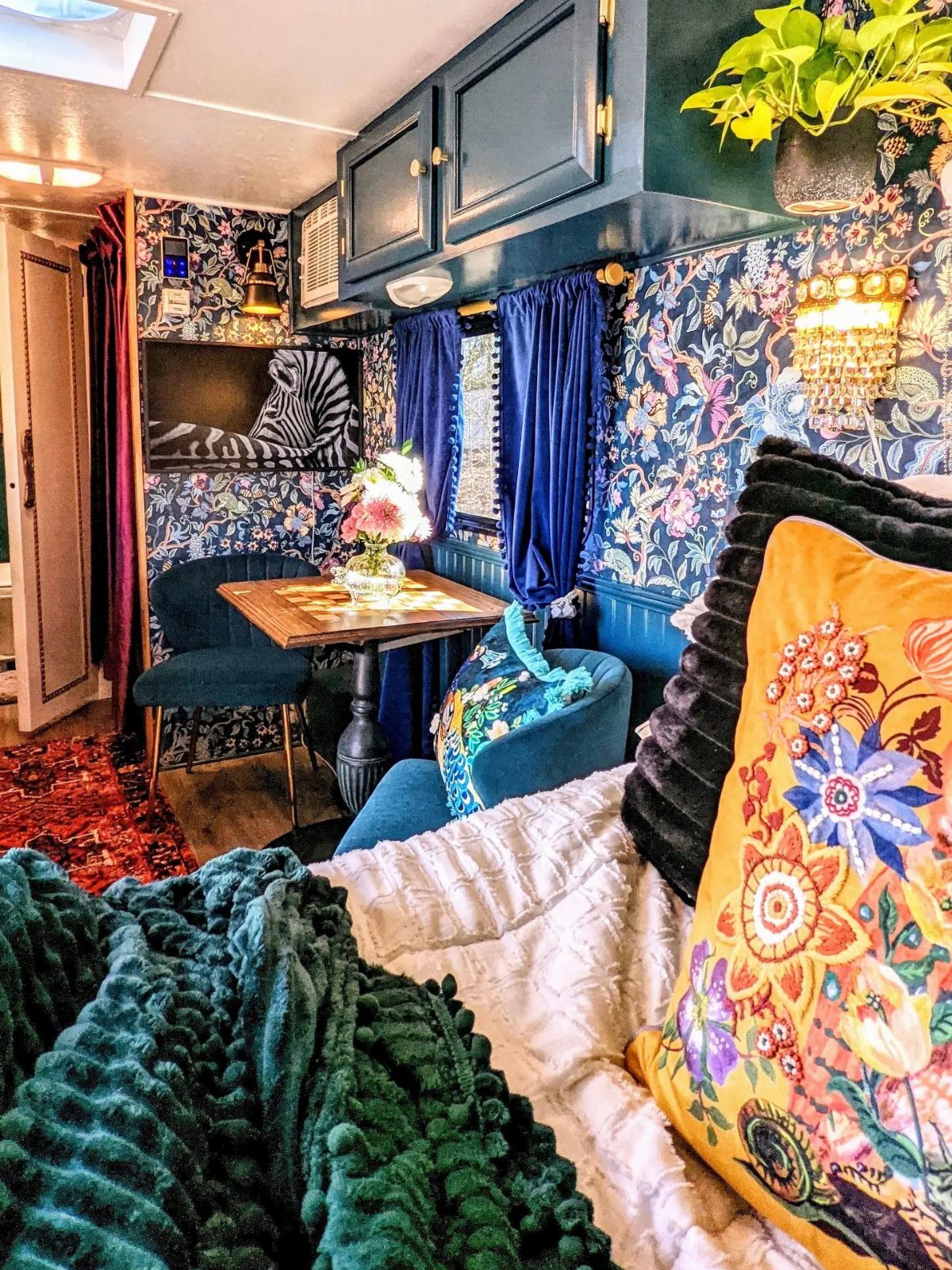 Blue velvet curtains and floral wallpaper inside a colorful, eclectic RV interior.