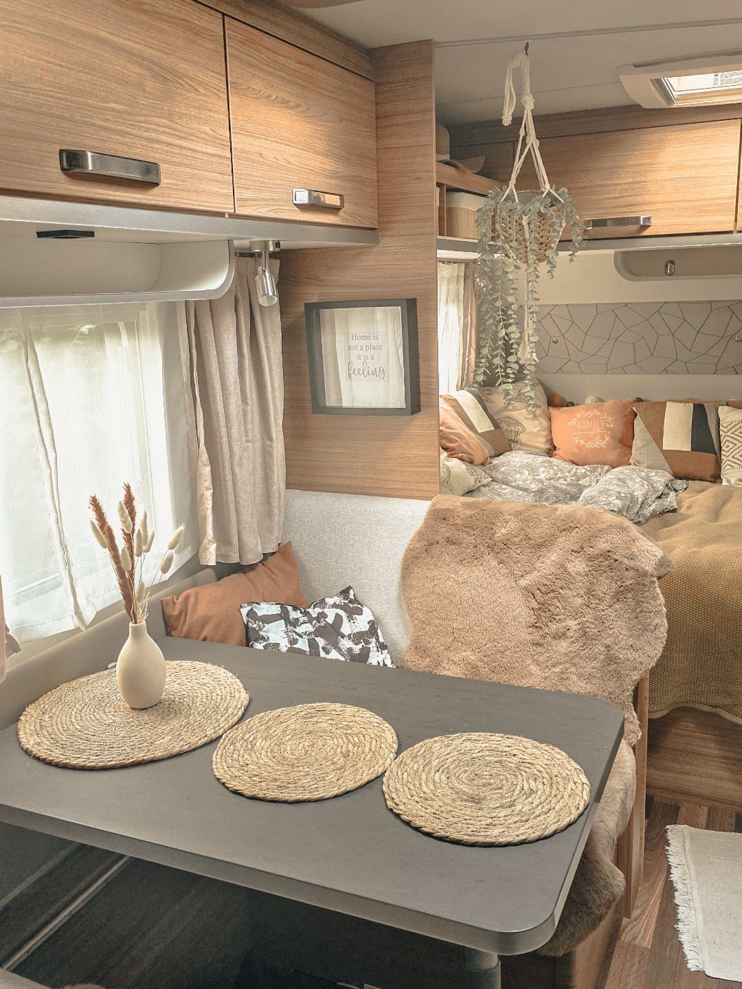 RV interior with woven placemats, a small vase, and cozy beige bedding.