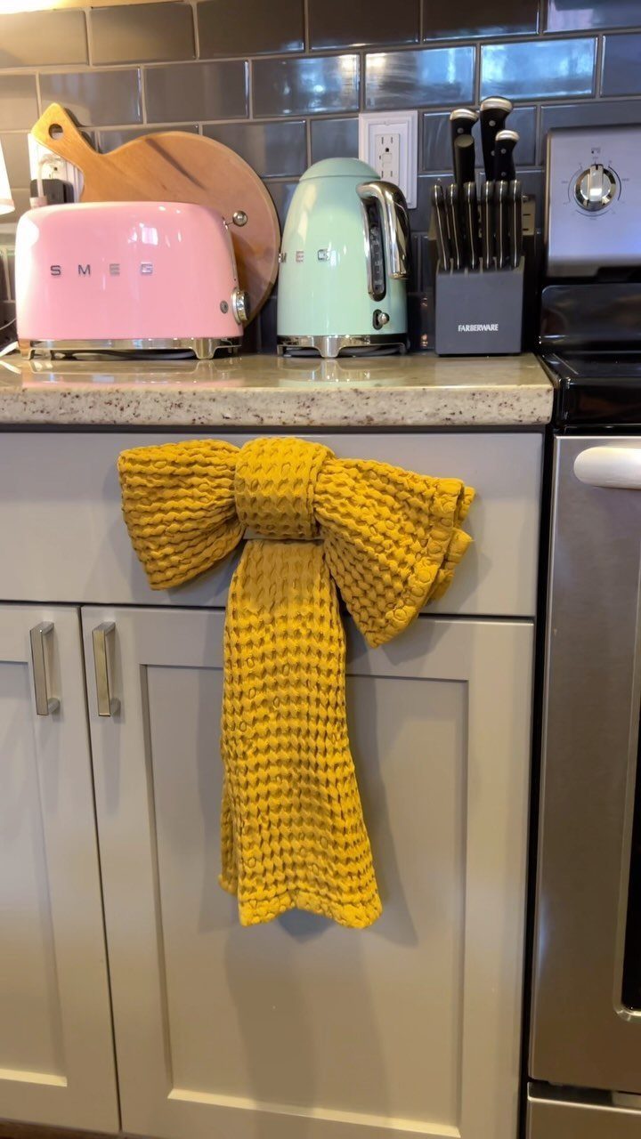 Yellow textured kitchen towel tied in a bow on a white cabinet handle.