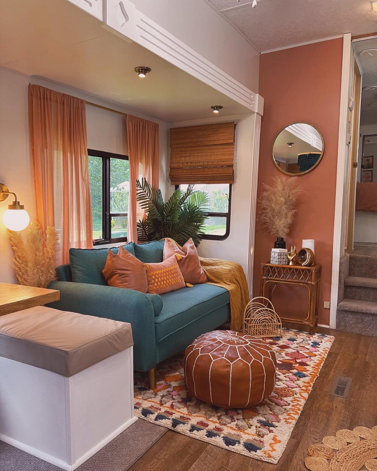 Teal sofa and terracotta wall in an RV with a large faux plant.