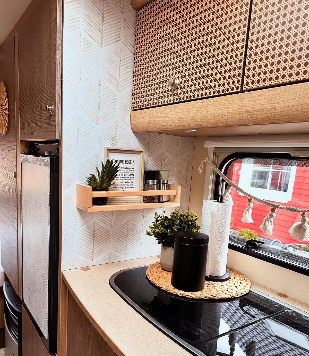 RV kitchen counter with a small wooden floating shelf and patterned wallpaper.