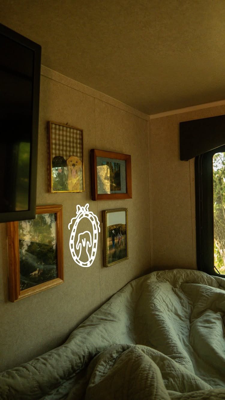 Framed pictures on a beige wall above a bed inside an RV interior.