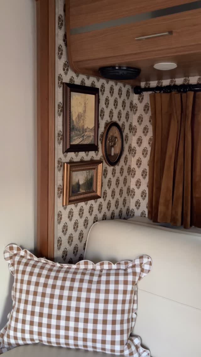 Patterned wallpaper and framed art decorating the interior wall of a cozy RV.