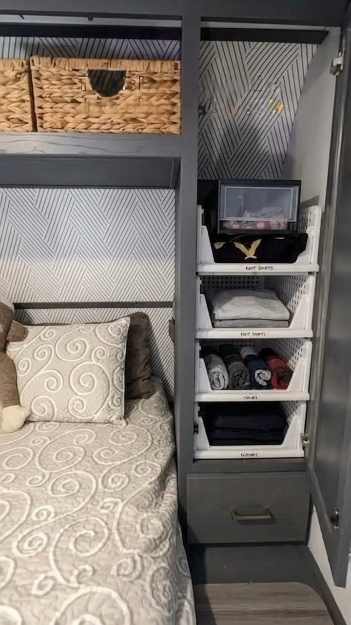 RV interior with chevron wallpaper, swirl patterned bedding, and hanging storage bins.
