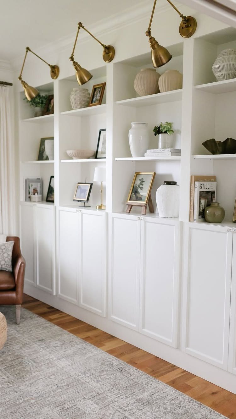 White built-in shelves decorated with vases, framed photos, and gold swing-arm lamps.
