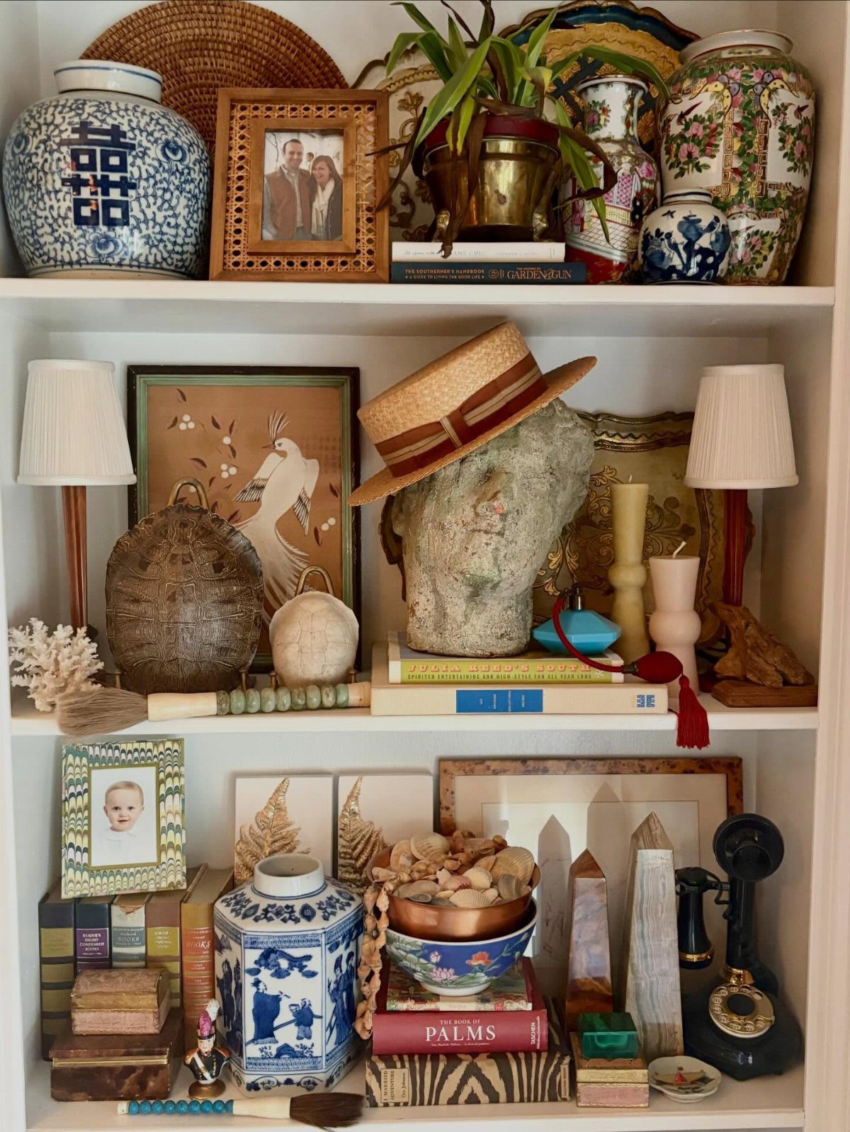 Eclectic shelf decor featuring vintage vases, framed family photos, and a classical bust.