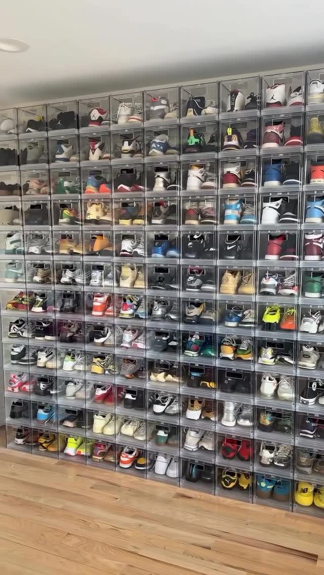 Clear plastic drop-front shoe boxes stacked in a large grid displaying various sneakers.