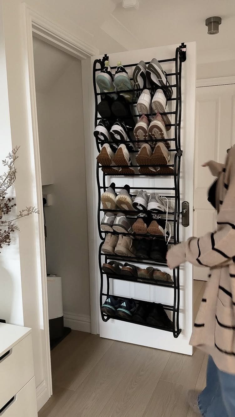 Black hanging shoe organizer on a white door filled with various sneakers and shoes.
