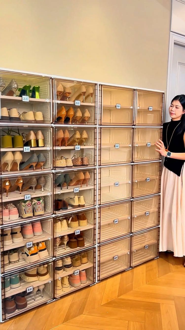 Woman standing by a wall of clear stackable plastic shoe storage boxes.