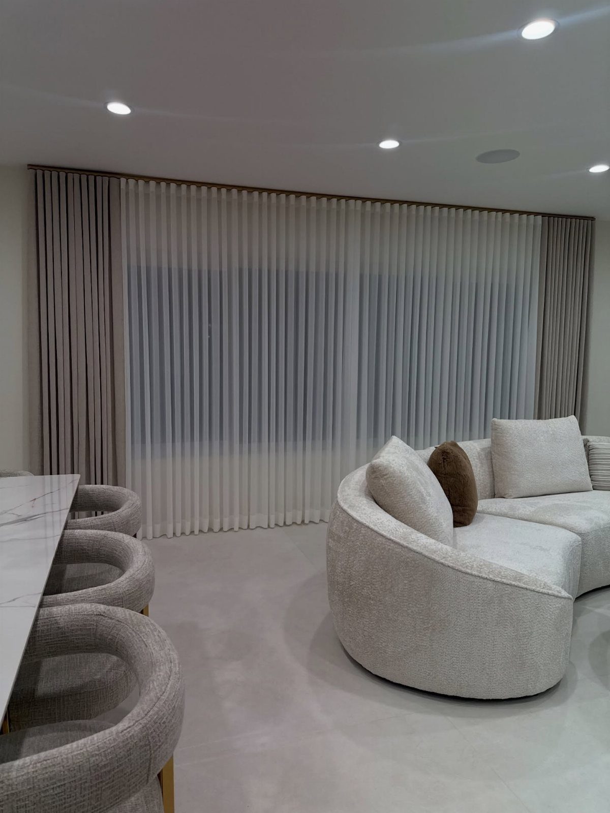 Beige and white floor-to-ceiling curtains blending with walls in a modern living room.