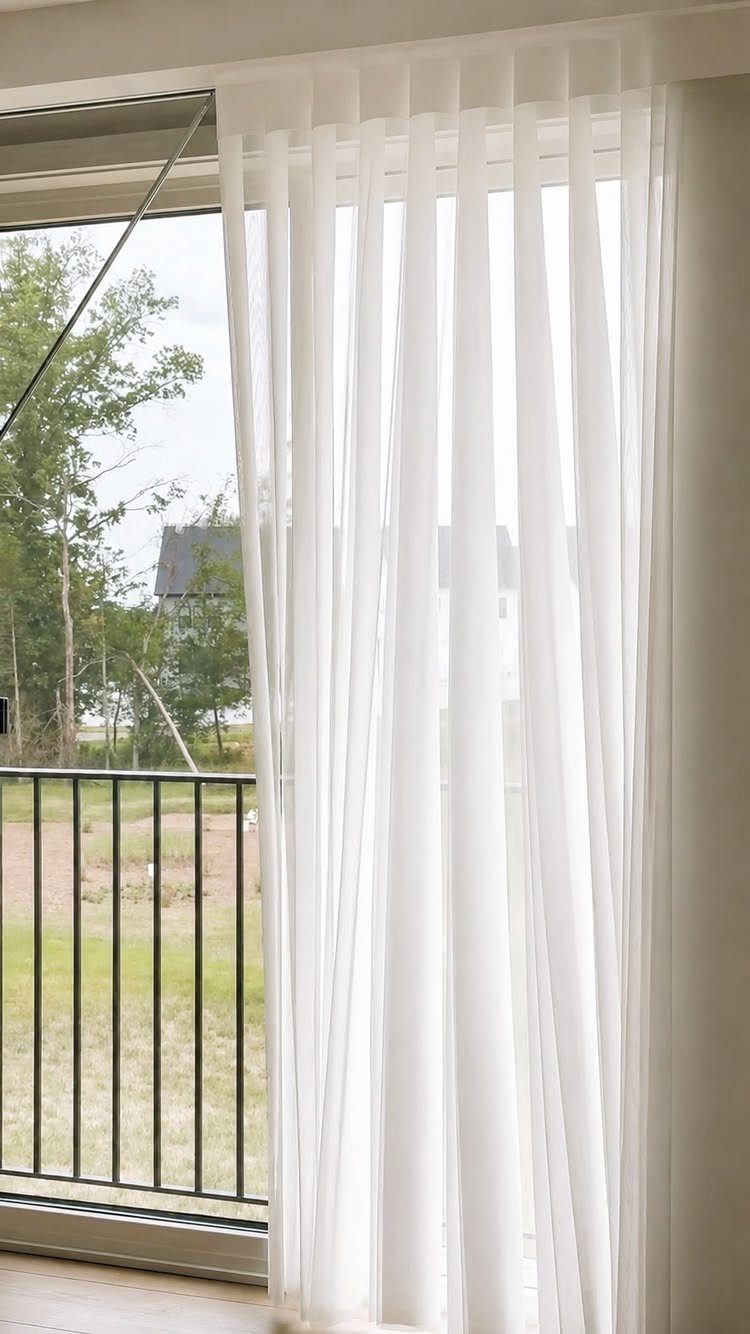 White sheer curtains covering a sliding glass door leading to a balcony.