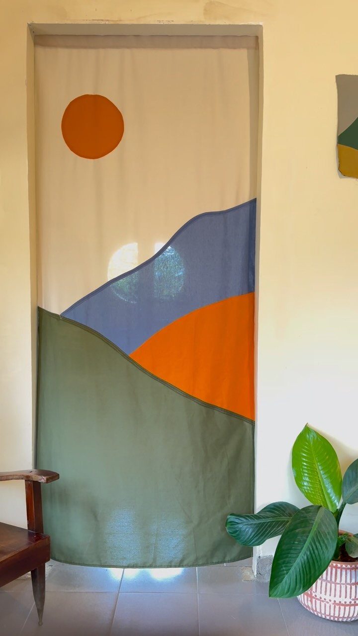Fabric door curtain with a minimalist nature print of a sun and hills.