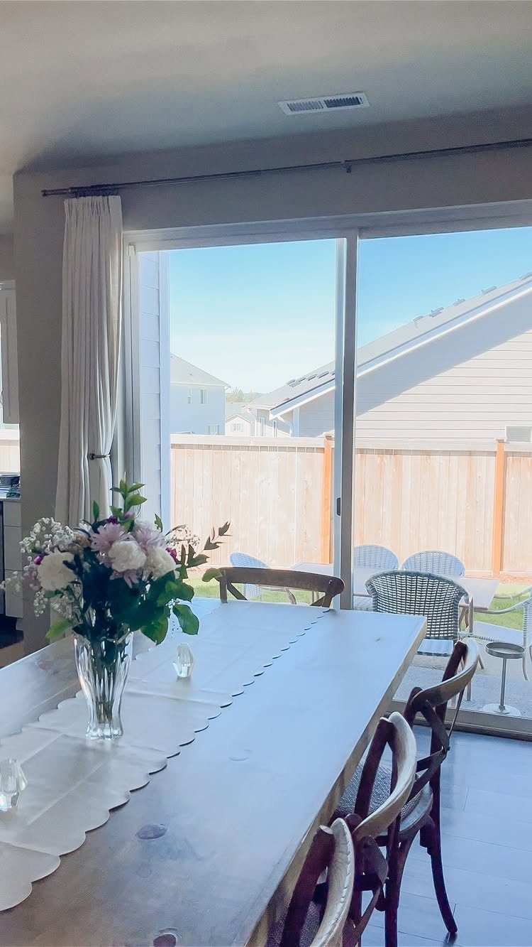 White curtain hanging beside a glass sliding door in a bright dining room.