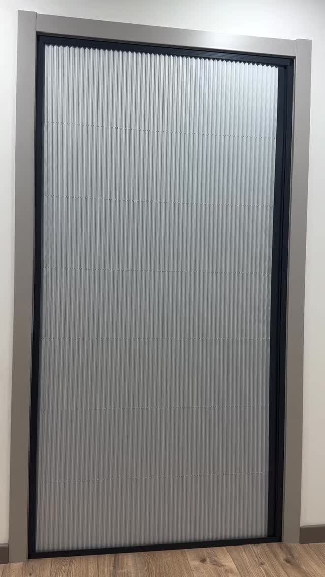 White ribbed sliding door curtain in a dark grey frame on wood floor