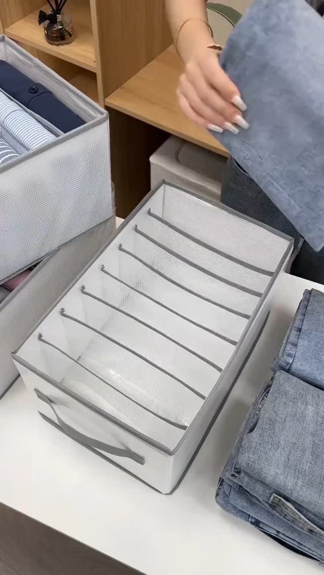 White fabric storage bin with dividers for organizing folded blue clothing in a closet.