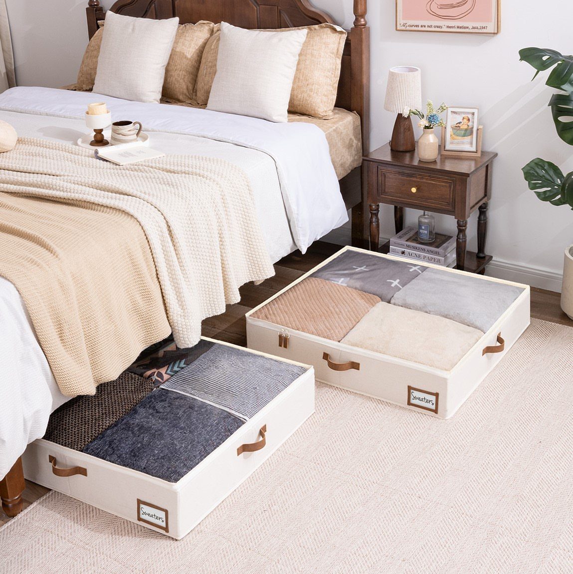 White under-bed storage bins filled with folded sweaters pulled out from beneath a bed.