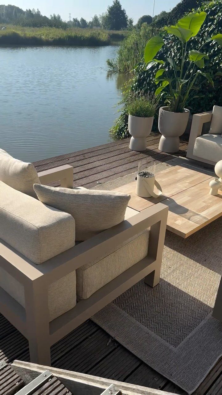 Modern beige outdoor lounge furniture and wooden table on a riverside deck