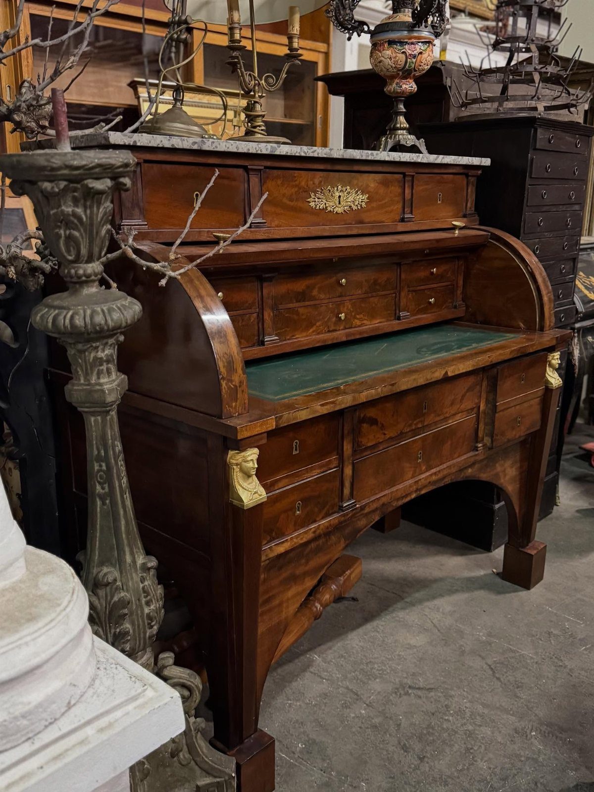 Antique roll-top desk made of dark wood with gold accents and green leather top.