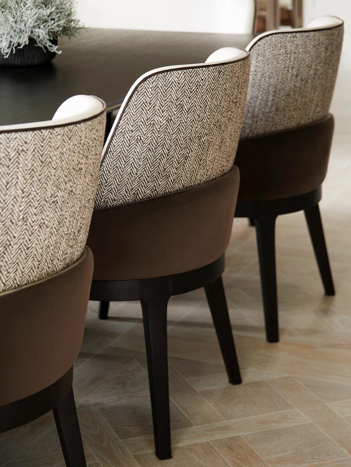 Modern dining chairs with brown fabric and beige herringbone patterns around a table.