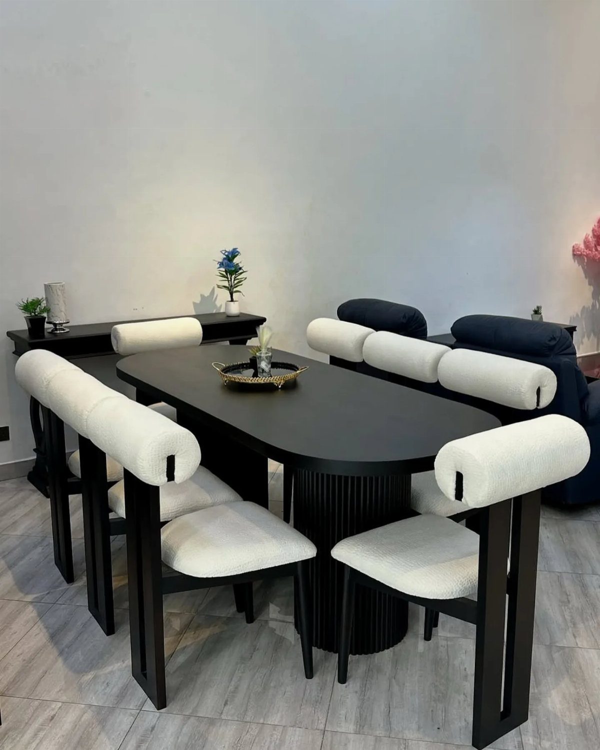 Black oval dining table with white modern chairs in a bright room