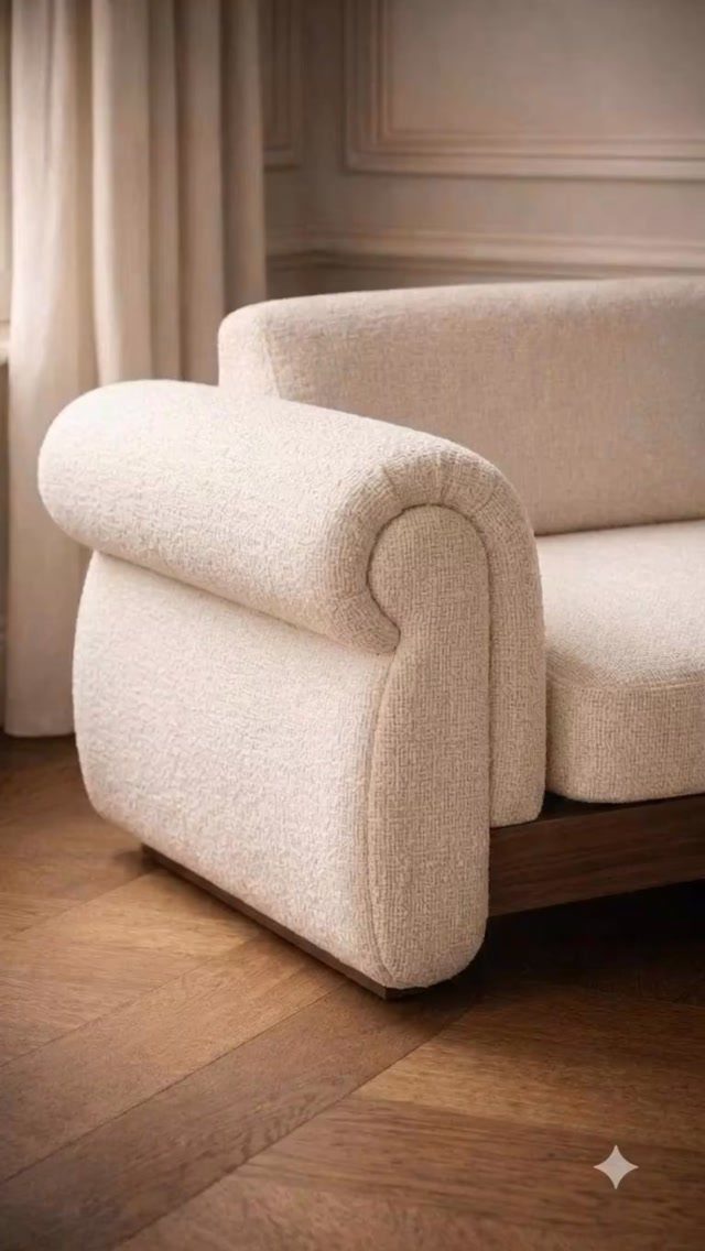 Cream bouclé sofa with rounded armrest on a herringbone wooden floor
