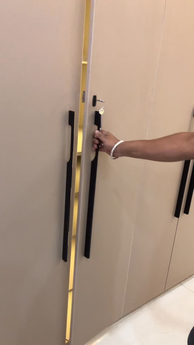 Beige storage cabinet with long black handles being opened by a person's hand