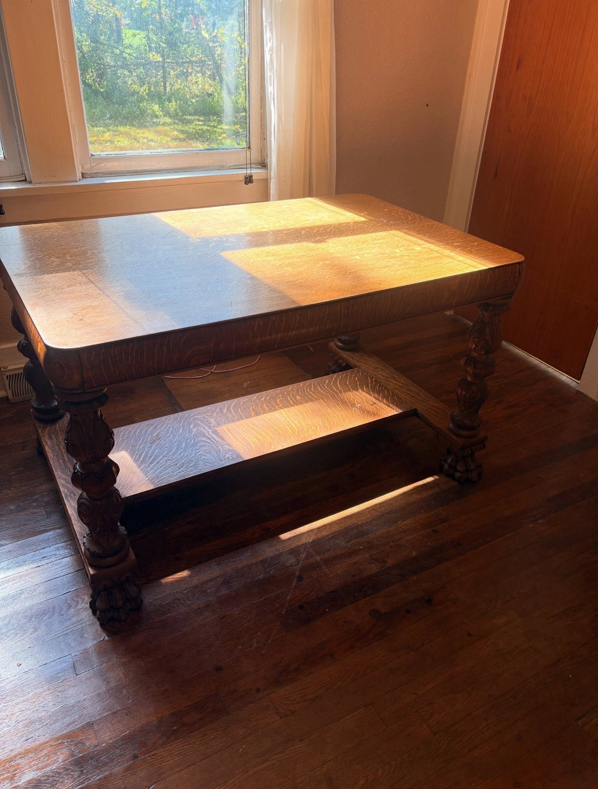 Wooden vintage coffee table with carved legs on a dark hardwood floor