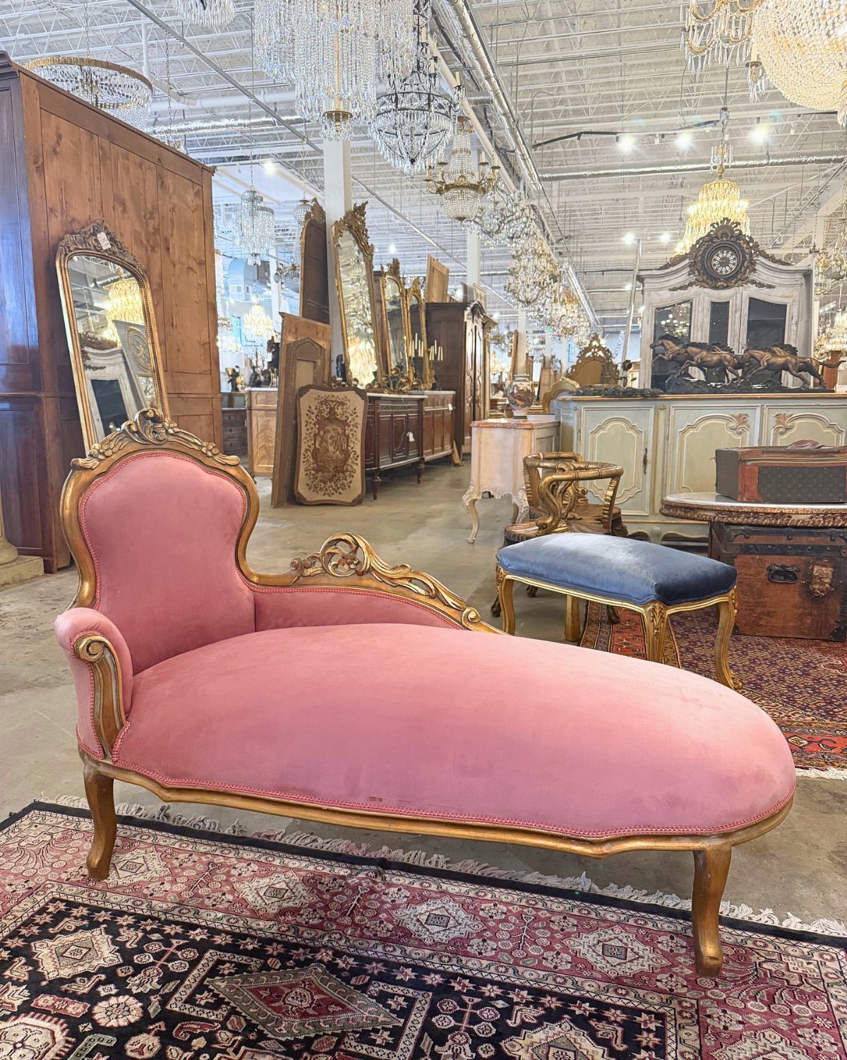 Pink velvet chaise longue with gold trim in a vintage furniture warehouse