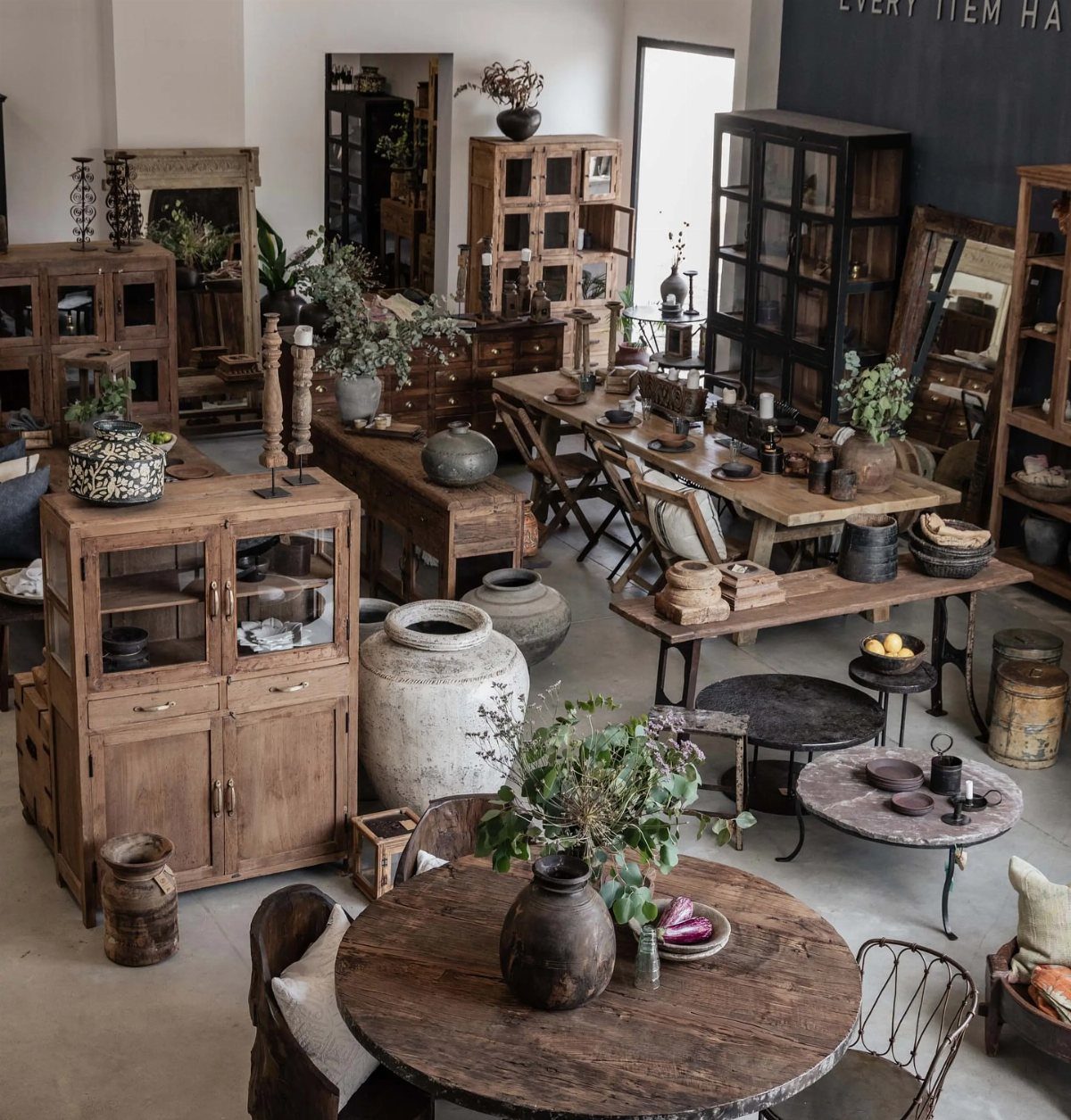 Rustic wooden furniture and ceramic pots arranged in a vintage boutique interior.